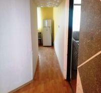 Folyosó egy háromszobás lakásban fa dekoros padlóval, amely a hűtőszekrényhez vezet.