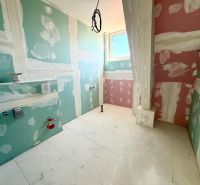 Fürdőszoba egy kétszobás lakásban, előkészítve a telepítésre, a padló a végső felületkezelésre vár.