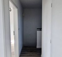 Egy családi ház folyosója fehér falakkal és fa dekorációjú padlóval.