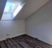 Tetőtéri szoba nagy tetőablakkal és fa dekorációjú padlóval egy családi házban.