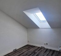 Tetőtéri szoba fa dekoros padlóval és tetőablakkal egy családi házban.