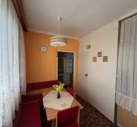 Konyha a kétszobás lakásban narancssárga fallal, szőnyeggel és csipkefüggönyökkel.