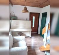 Családi ház belső tere fehér zongorával, fa dekorációjú padlóval, lépcsőkkel és fa mennyezettel.