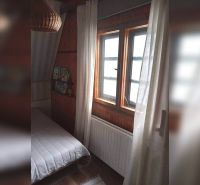 Szoba egy családi házban sötét fa burkolattal és ággyal az ablak mellett.