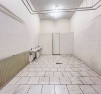 Raktárak és csarnokok belső tere fehér falakkal, két mosdóval és csempézett padlóval.