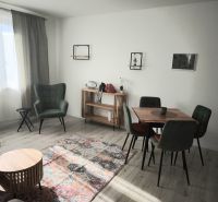 Nappali egy kétszobás lakásban zöld fotellel és fa padló dekorációval.