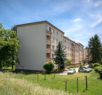 A Švermova utcai lakóházak Trencsénben a környező zöldterülettel és parkoló autókkal.