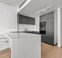 Minimalista konyha egy háromszobás lakásban a Továrenská utcában, modern felszereléssel és bárszékekkel.