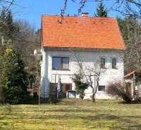 Családi ház Kráľovában, Besztercebányán, piros tetővel, zölddel és fákkal körülvéve.
