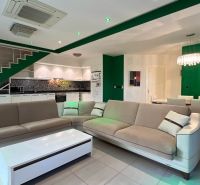 Rekreációs apartman tágas kanapéval, fehér konyhaszekrényekkel és étkező feletti lámpával.