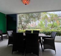 A nyaraló apartmanban rattan bútorok vannak, kilátással a kertre.