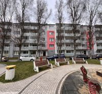Egy lakóház Rózsahegyen, fákkal és parkolóhelyekkel a kétszobás lakások előtt.