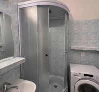 Fürdőszoba zuhanyzóval és mosógéppel egy kétszobás lakásban.