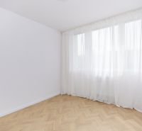 Tágas szoba fa mintázatú padlóval és fehér függönyökkel egy 4 szobás lakásban.