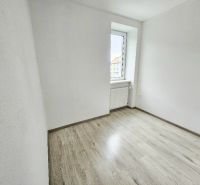 Egy szoba az egyszobás lakásban fa dekorációval ellátott padlóval és világos fallal.