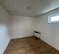 Szoba fa dekorációjú padlóval és fehér falakkal egy kétszobás lakásban.