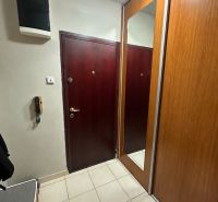 Előszoba egy háromszobás lakásban tükrös gardróbszekrénnyel és világos csempével.
