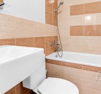Fürdőszoba a garzonlakásban káddal, mosdóval és WC-vel, sima csempék világos árnyalatokban.