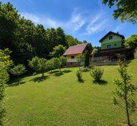 Házikó a Klučina-ban, Považská Bystrica-ban, gondozott kerttel, fákkal és zöld fűvel.