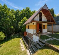 Faház fa dekorációval Považská Bystricában, Klučina területén, zölddel és fákkal körülvéve.