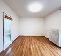 Szoba egy kétszobás lakásban fa dekor padlóval és radiátorral.