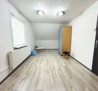 Szoba egy családi házban fa dekorációjú padlóval és egyszerű bútorokkal.