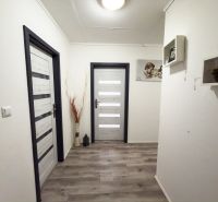Folyosó egy családi házban fa dekor padlóval és dekoratív polcokkal.