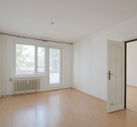 Nappali egy háromszobás lakásban fa dekor padlóval és radiátorral.