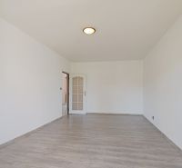 Tágas szoba fa dekor padlóval egy háromszobás lakásban, fehér falakkal.
