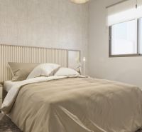 Nyaraló apartman hálószobája ággyal, mintás fallal és nagy ablakkal.