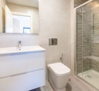 Fürdőszoba a nyaraló apartmanban nagy zuhanyzóval és elegáns mosdóval.