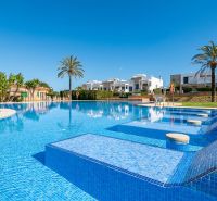 Medence a Cala Murada-i nyaraló apartman mellett Mallorcán, pálmafákkal és napozóágyakkal.
