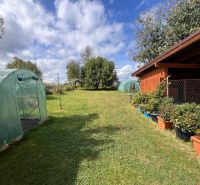 Egy családi ház kertje Bacúchon fóliasátrakkal és pavilonnal, növényekkel körülvéve.