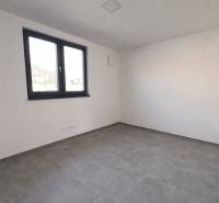 Üres szoba csempével, fehér falakkal és nagy ablakkal egy családi házban.