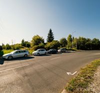 Út parkoló autókkal és hirdetőtáblával a Partizánska úton, Besztercebánya, Lakóterületek.