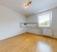 Szoba egy háromszobás lakásban, fa dekorációjú padlóval és nagy ablakkal.