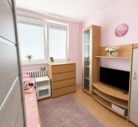 Gyerekszoba fa mintázatú padlóval, rózsaszín falakkal és fa bútorokkal egy háromszobás lakásban.