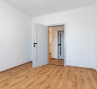 Fehér szoba fa dekorációjú padlóval és ajtóval egy háromszobás lakásban.