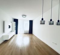 Nappali egy háromszobás lakásban, fa dekorációjú padlóval és függőlámpákkal.
