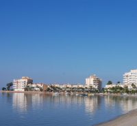 La Manga del Mar Menor tengerpartja rekreációs apartmanokkal a nyugodt tenger és a kék ég alatt.