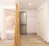 Nyaraló apartman belső tere konyhaszekrényekkel, hűtőszekrénnyel és fa dekorációjú padlóval.