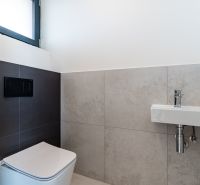 Függesztett WC-vel és mosdóval ellátott fürdőszoba családi házban.