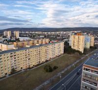 Kilátás a pozsonyi Dúbravka lakótelepre Janko Alexy utcából, zölddel és úttal körülvéve. Garzonlakás.