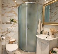 Fürdőszoba a garzonlakásban modern zuhanyzóval, WC-vel és dekorációkkal.