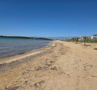 Homokos strand náderná napernyőkkel Privlakában, kék éggel és tengerrel.