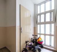 Folyosó gyerekbiciklivel az ablaknál és az ajtónál egy háromszobás lakásban.