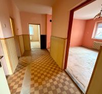 Világos belső tér egy családi házban csempézett padlóval, rózsaszín falakkal és fa burkolattal.