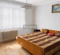 Hálószoba családi házban, fa dekorációjú padlóval és radiátorral az ablak mellett.