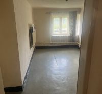 Szoba egy családi házban betonpadlóval és bejövő fényt árasztó ablakkal.