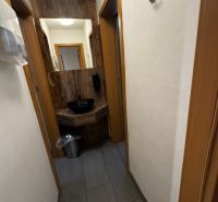 Az üzlethelyiségek folyosója sötét padlóval és fehér falakkal.
